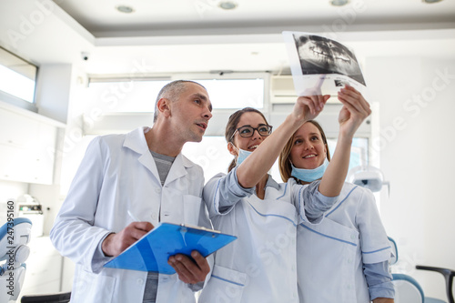 In a busy dental office, a group of dentists examining x-ray image of the patient's teeth to provide accurate diagnoses and develop effective treatment plans.