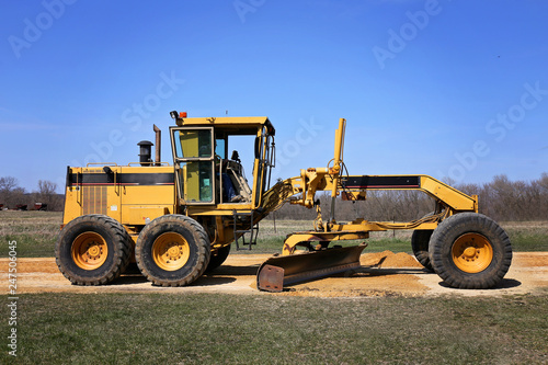 Big Road Grader Construction Truck Working on Rural Gravel Driveway