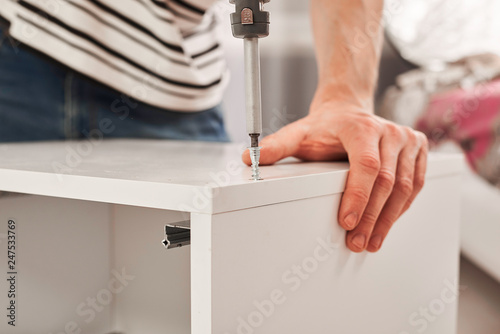 The furniture assembler joins together the two parts of the ready-to-assemble furniture with cam lock connections and wooden dowel pin, flat pack furniture assembly service, snap-together joints