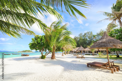 Empty sunny Koh Lipe Beach with tall palms and beach bungalows