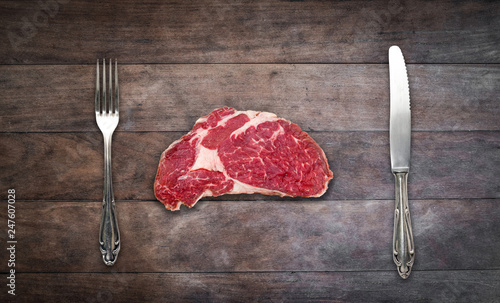 slice red meat / raw steak with knife and fork on wooden background