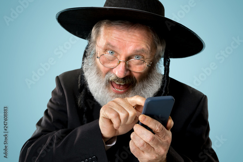 Portrait of old senior orthodox Hasdim Jewish man with mobile phone at Jewish festival of Purim at studio. The purim, jewish, festival, holiday, celebration, judaism, tradition, business