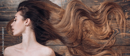 Woman with beautiful long hair on wooden background. Long hair. Trendy haircuts. Beauty hair Salon.