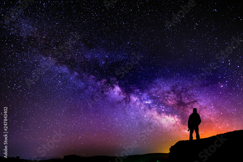 Beautiful starry night, man silhouette with a camera looking at the Milky Way galaxy.