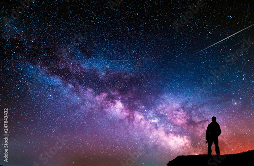 Beautiful starry night, man silhouette with a camera looking at the Milky Way galaxy.