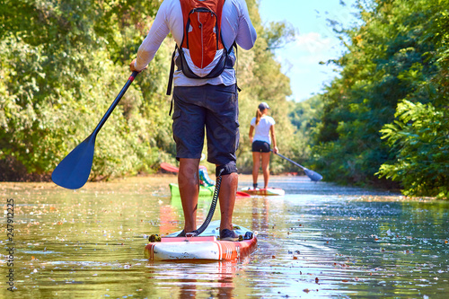 Close-up of a woman and man legs on stand up paddle in water