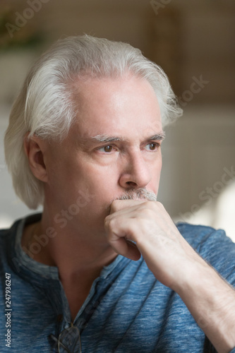 Focused puzzled grey haired man at home