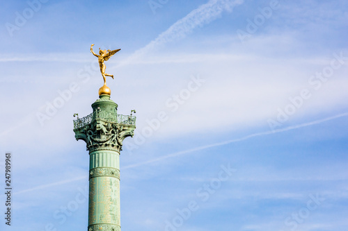 The Genius of Liberty golden statue, by french sculptor Auguste Dumont, atop the July Column in the center of Place de la Bastille in Paris, France, against blue sky.