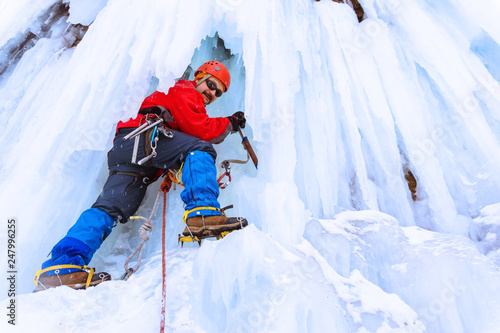 ice climber on a vertical wall of a frozen waterfall