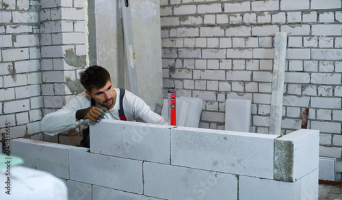 builder checking evenness of aerated concrete wall with spirit level