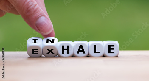 Inhale,Exhale concept. Hand turns dice and changes the word "INHALE" to "EXHALE".