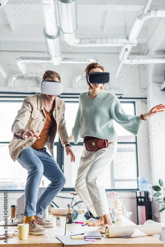 female and male designers gesturing with hands while having virtual reality experience in loft office