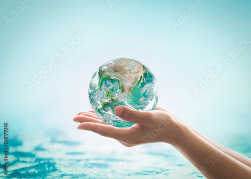 World ocean day, saving water campaign, sustainable ecological ecosystems concept with green earth on woman's hands on blue sea background : Element of this image furnished by NASA .