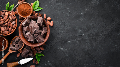 Cocoa beans, chocolate, cocoa butter and cocoa powder on a black background. Top view. Free copy space.
