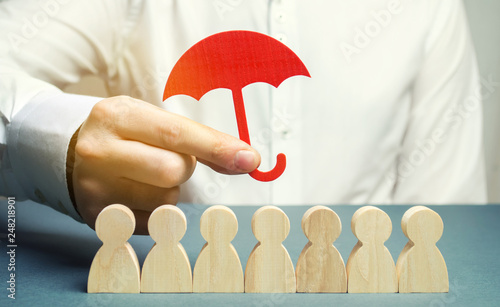 Boss holding a red umbrella and defending his team with a gesture of protection. Life insurance. Customer care, care for employees. Security and safety in a business team. Selective focus