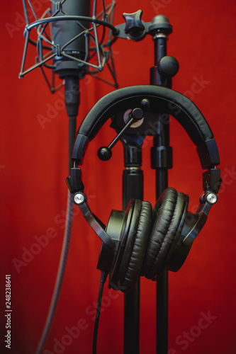 Microphone for recording music and headphones in the studio. Red background.