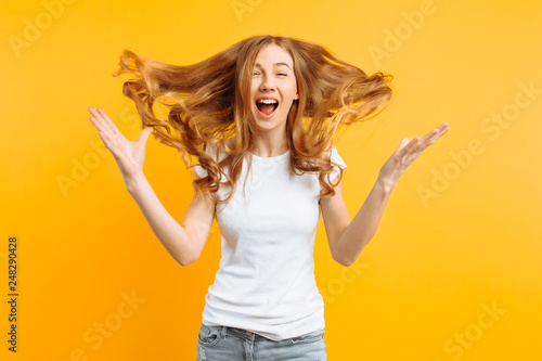 Young shocked girl shocked by good news, screaming with happiness over yellow background