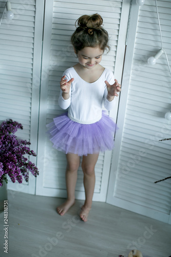 Adorable little girl dressed as a ballerina in a tutu, tying her ballet slippers.