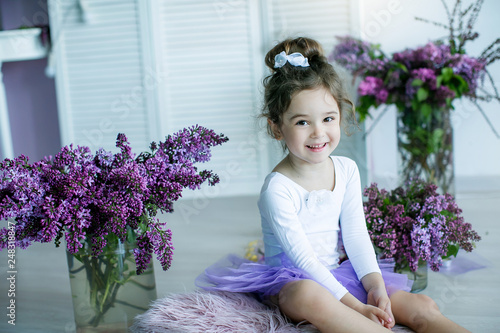 Adorable little girl dressed as a ballerina in a tutu, tying her ballet slippers.