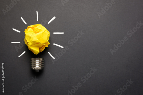 Great idea concept with crumpled yellow paper light bulb isolated on dark background