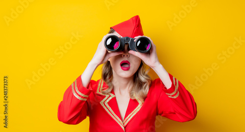 charming vintage stewardess wearing in red uniform with binoculars