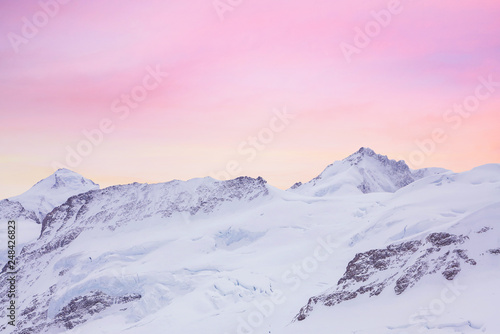 Snowy summits of mount Jungfrau in the Bernese Alps against the backdrop of sunset sky in the pastel color, Switzerland