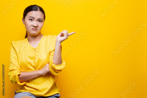 Woman show disgust gesture isolated over yellow background