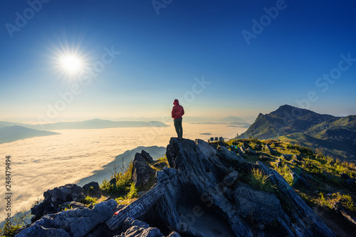Traveler standing on the rock, Doi pha tang and morning fog in Chiang rai, Thailand.