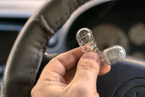 new and burnt out car light bulb, in man's hand