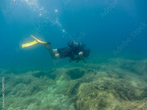 Young man with diving equipment swimming underwater.Scuba diving in Ionian sea. Greece, Corfu vacation summer