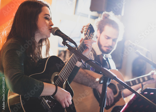 Duet of guitarists singing during a musical performance.