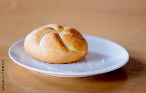 Kaiser roll on a plate on wooden table