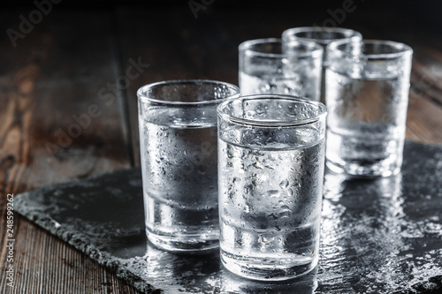 Vodka in shot glasses on rustic wood background