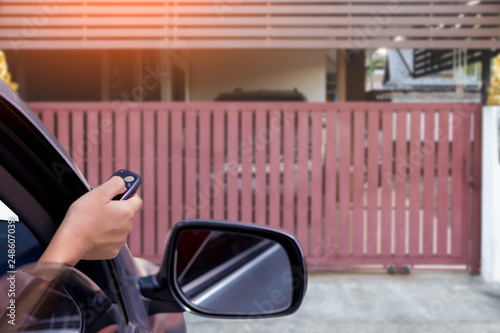 Woman in car, hand opening the automatic gate by using remote control. The auto door and security system concept.