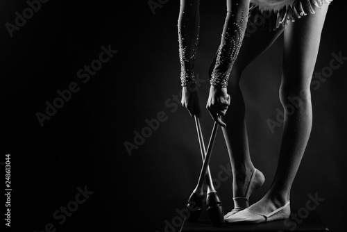 Teenager girl gymnast holds in hands clubs for rhythmic gymnastics.near the legs