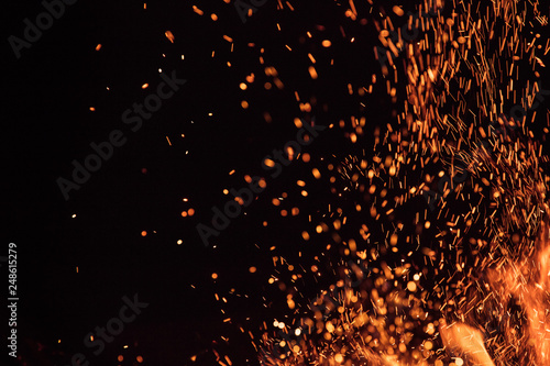 Burning sparks flying. Beautiful flames. Fiery orange glowing flying away particles on black background.