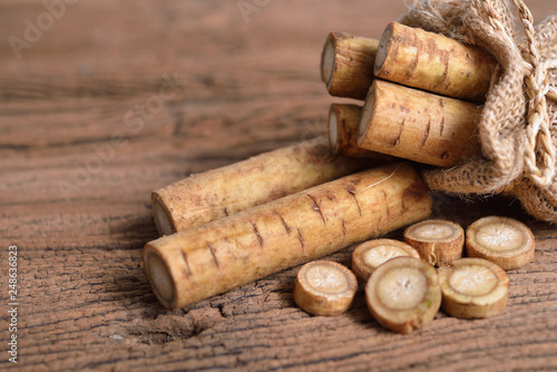 fresh burdock root or Gobo in sack and on wooden background