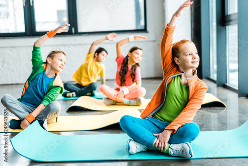 Happy kids stretching on fitness mats with smile