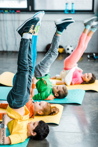 Kids doing candlestick exercise on mats in gym