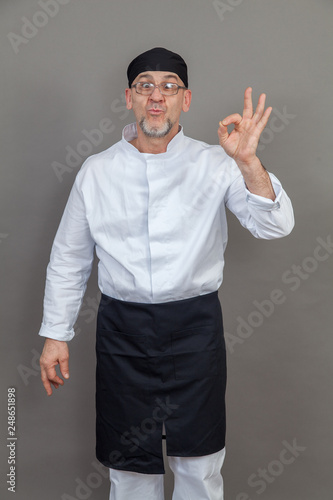 Elderly chef on grey background, isolated, concept