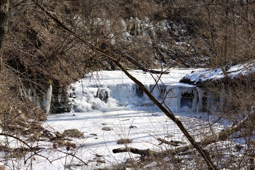 A view of the frozen waterfall in the forest on a sunny day.