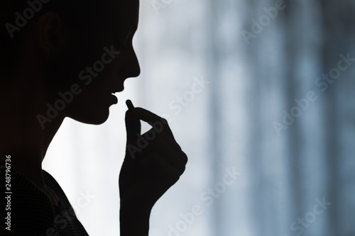 Medicine, health care and people concept. Close up of young woman taking in pill