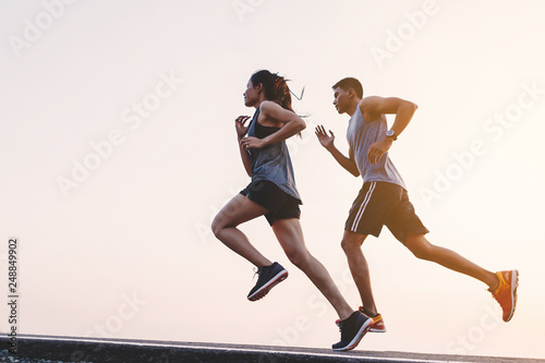 young couple runner running on running road in city park