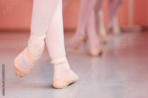 Close-up of teenage ballerina's feet, practicing ballet moves in a dancing studio. Low angle view, unrecognizable people