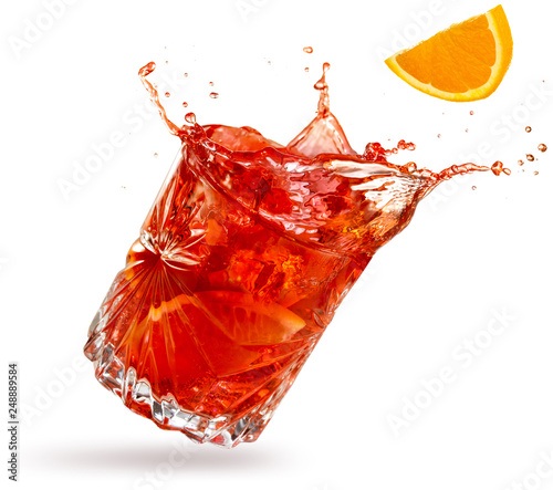 orange slice falling into a splashing negroni tilted on white background