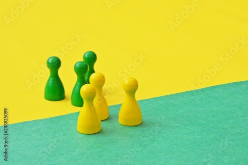 A red and a blue team of wooden game characters of a board game face each other and are greeted by the respective oppositely colored background - concept of boundaries and differences