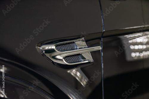 Ventilation grille in the wing of luxury very expensive new black car stands in the washing box waiting for repair in auto service