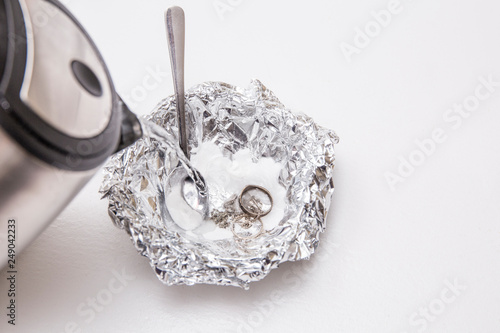 A solution of baking soda(Sodium bicarbonate) and warm water will remove the tarnish from silver when the silver is in contact with a piece of aluminium tin foil. Pouring hot water over silver.