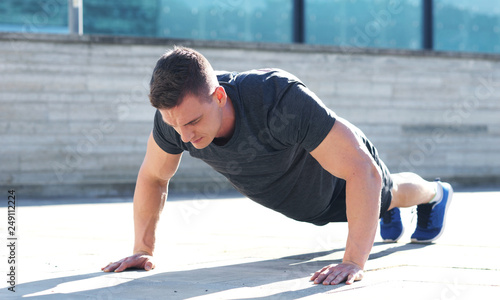 Young and sporty man training outdoor in sportswear. Sport, health, athletics.