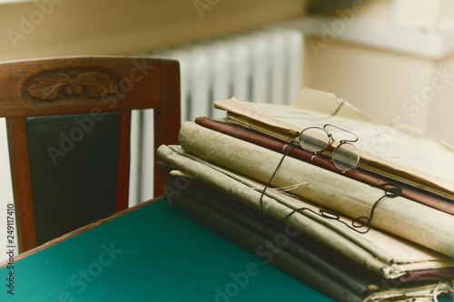 On the table with green cloth are old folders with papers and pince-nez,